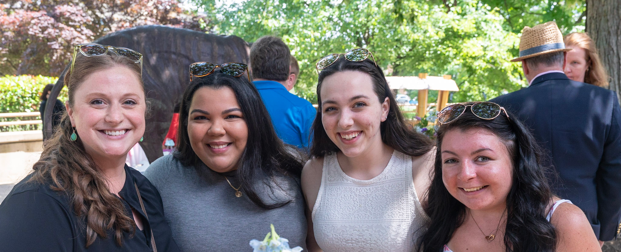 Four smiling students stand together outside of the Campus Center